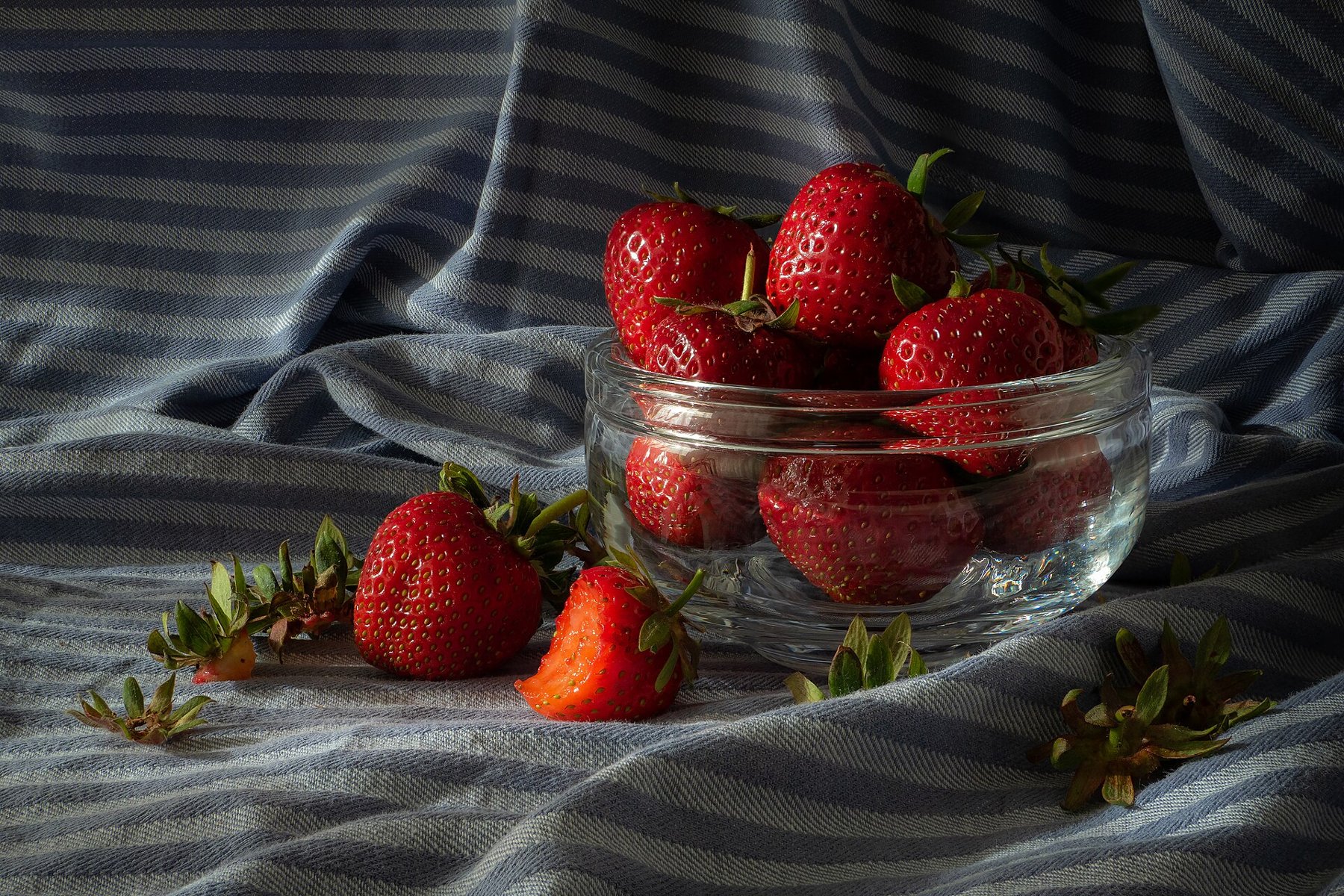 Strawberries in a glass bowl arranged as a still life.