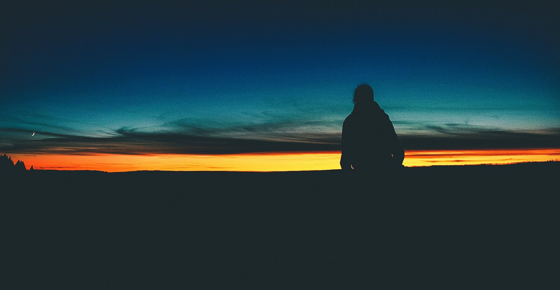 A person silhouetted against a bright horizon.